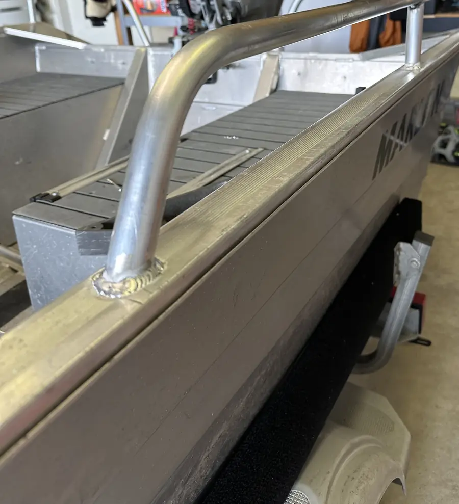 Bent aluminum grab rail welded onto the side of an aluminum boat