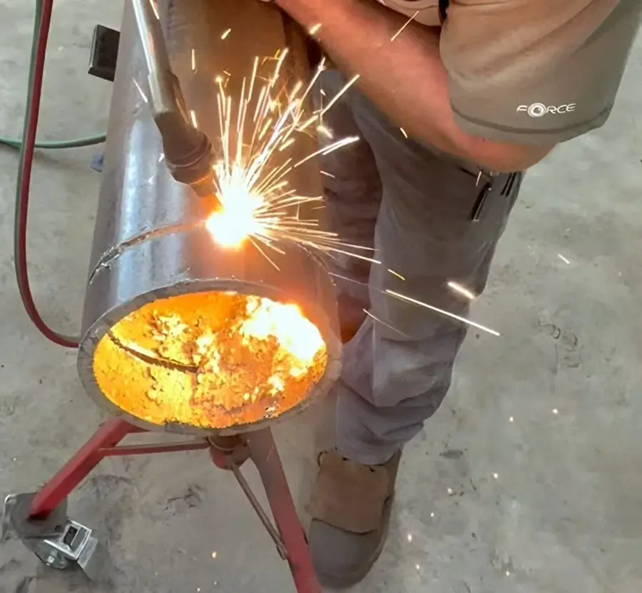 Cutting torch throwing sparks on steel pipe in Neal's McMinnville shop