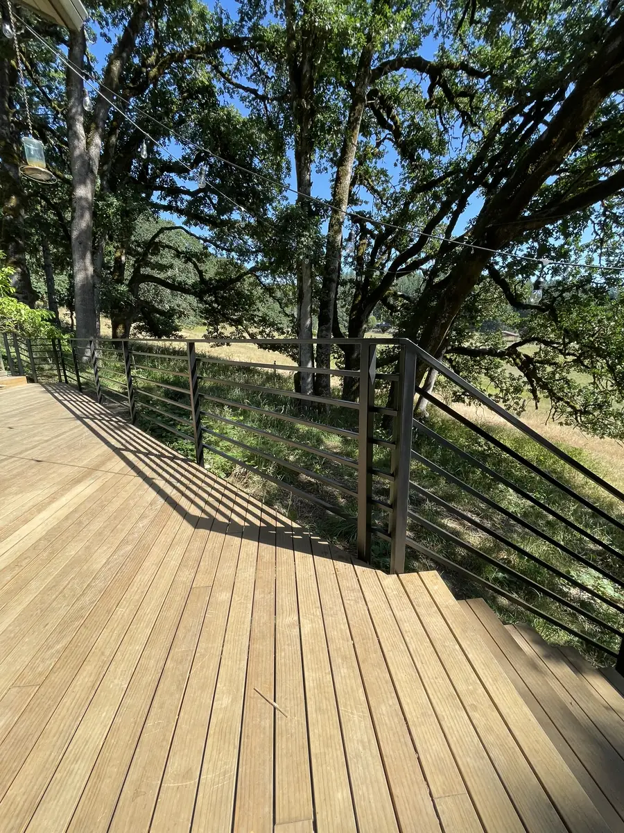 Horizontal bar steel railing around a deck under oak trees