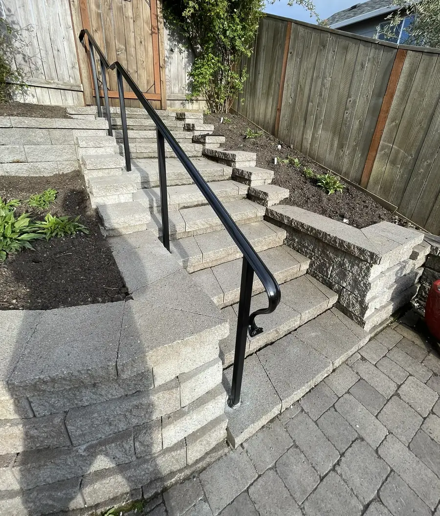 Black steel handrail up a set of paver steps