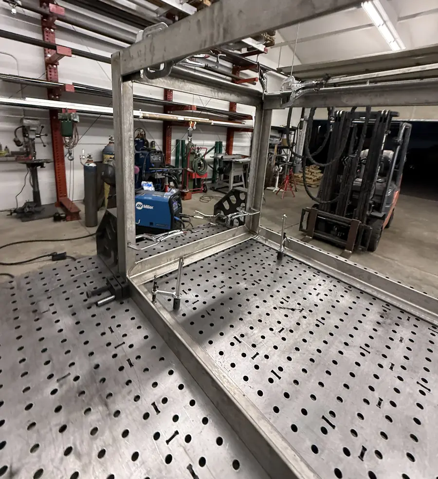 Corner of a stainless box frame clamped down on the fixture table
